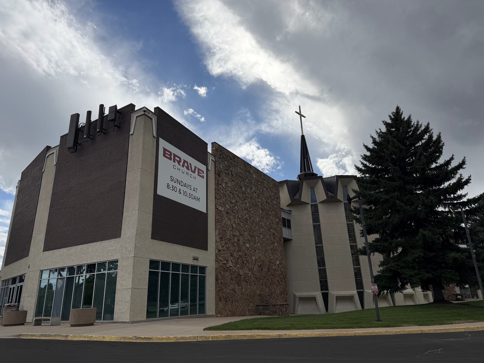 Church exterior with a tall metal spire, stained glass windows and a fluted metal roof
